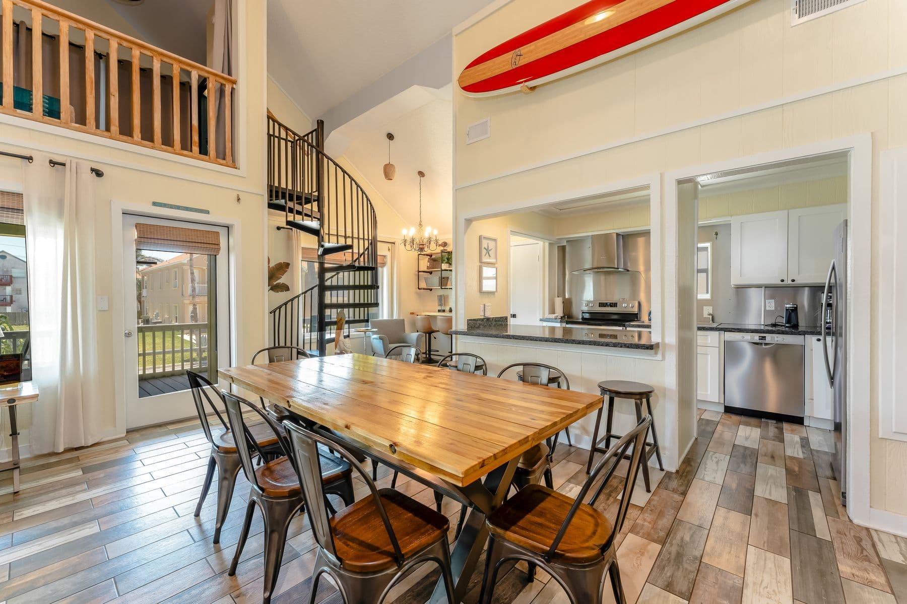 Dining area with surfboard art and kitchen beyond