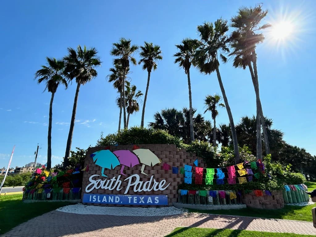South Padre Island welcome sign with palms against a clear blue sky